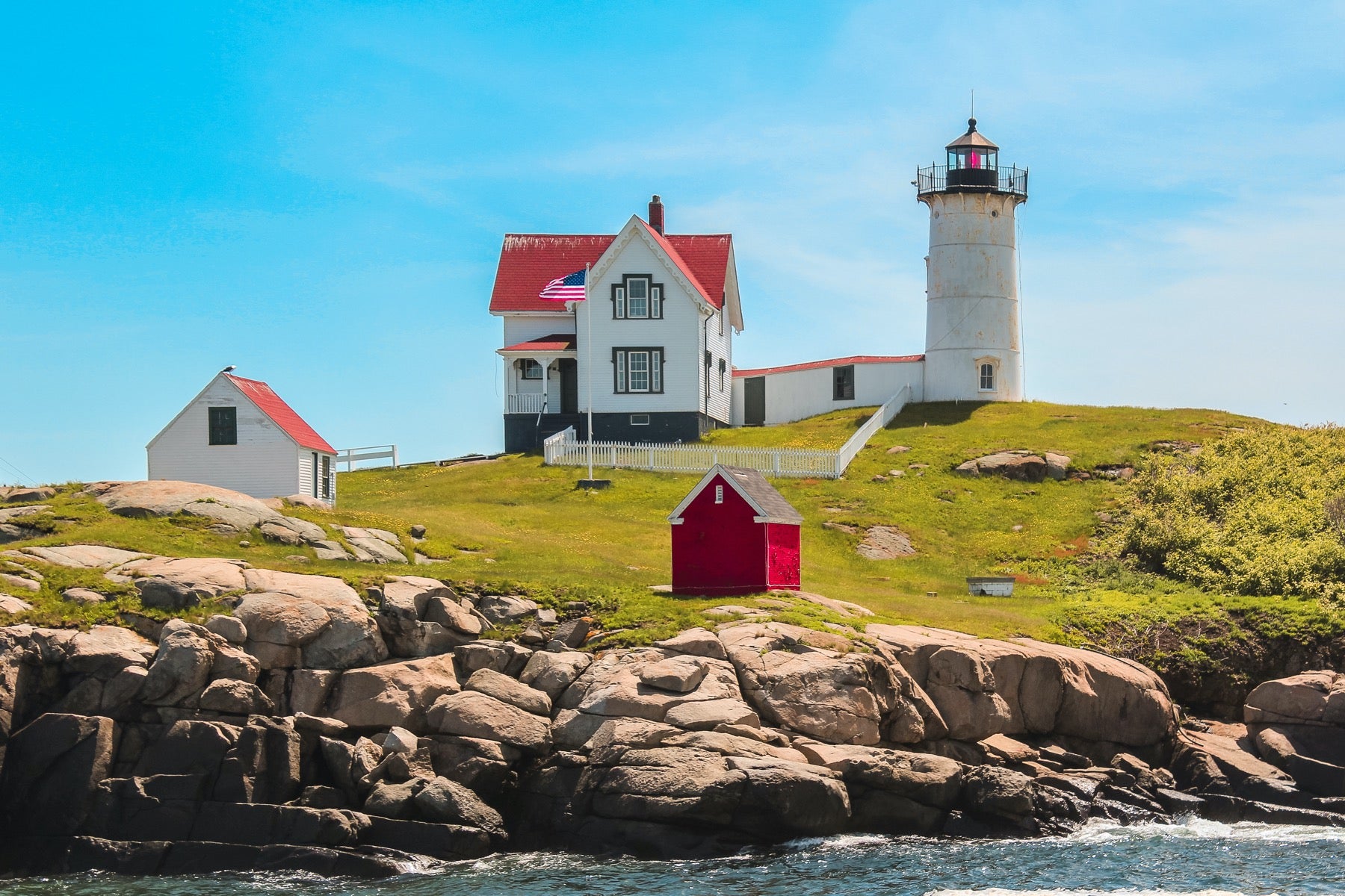 White lighthouse on a hill along the water