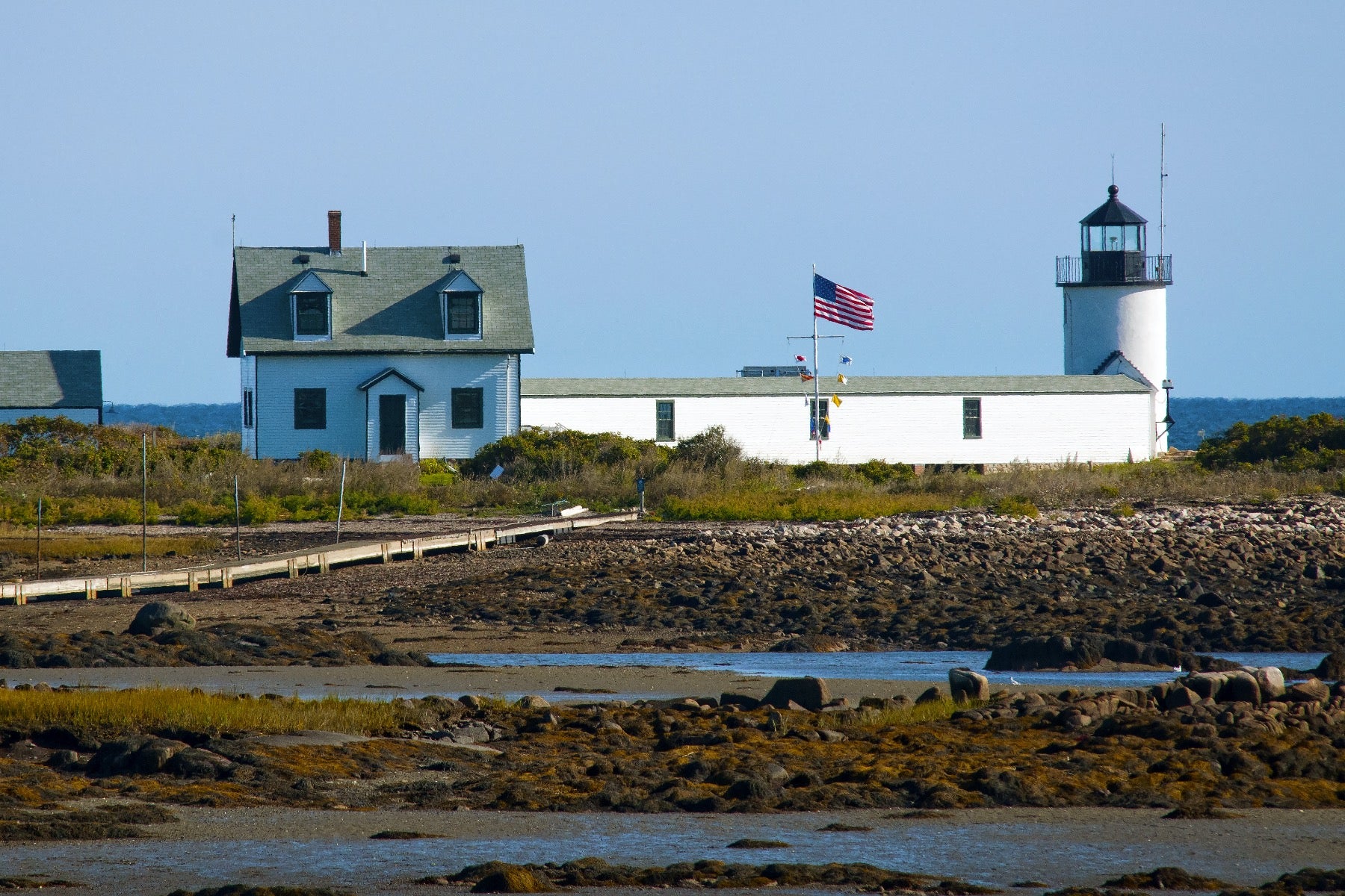 Lighthouse and american flag along the water